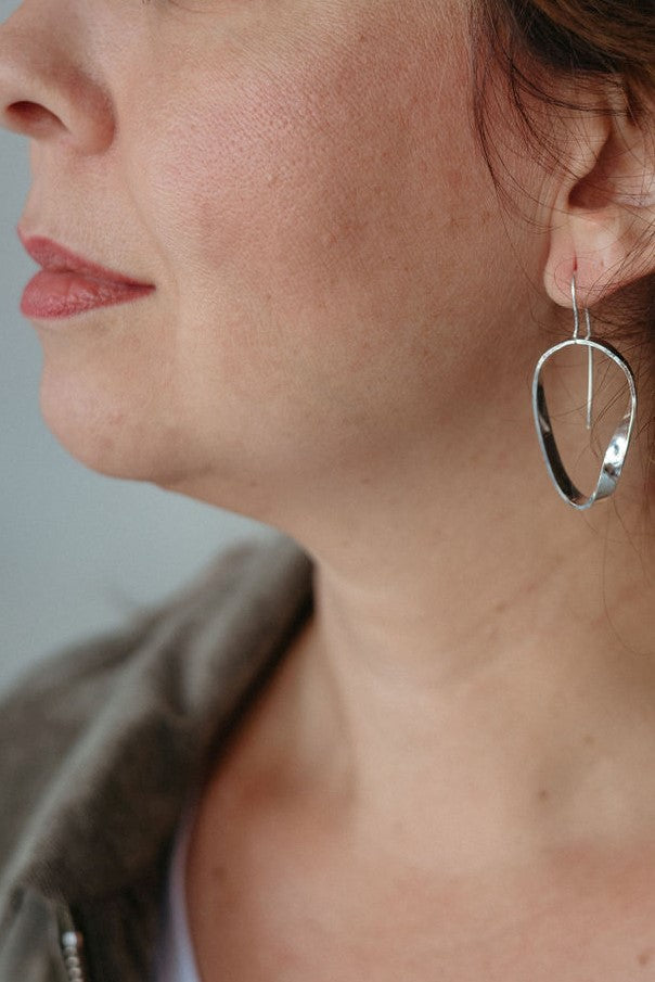 MODEL WEARING A PAIR OF STERLING SILVER MOBIUS DANGLE EARRINGS